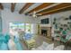 Cozy living room with a fireplace, TV, blue furnishings, and an open sliding door to the pool at 102 77Th St, Holmes Beach, FL 34217