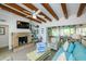 Bright living room with a stone fireplace, TV, exposed beams, and blue accents at 102 77Th St, Holmes Beach, FL 34217