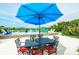 Charming outdoor patio with dining set under a large umbrella overlooking a tranquil backyard pool at 102 77Th St, Holmes Beach, FL 34217