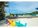 Vibrant pool deck features colorful Adirondack chairs, creating a fun and inviting outdoor space at 102 77Th St, Holmes Beach, FL 34217