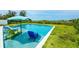 Relaxing backyard pool featuring built-in seating, an umbrella, and manicured grass for outdoor enjoyment at 102 77Th St, Holmes Beach, FL 34217