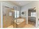 Bathroom with a tub, glass shower, and tile walls, plus access to the main bedroom at 11254 82Nd St E, Parrish, FL 34219