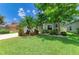 Charming single-story home featuring a well-manicured lawn with lush tropical landscaping and mature trees at 11254 82Nd St E, Parrish, FL 34219