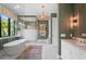 Bright bathroom featuring modern soaking tub, glass shower, white vanity, decorative lighting, and a garden view window at 1182 Blue Shell Loop, Sarasota, FL 34240
