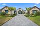 Beautiful home exterior with a brick driveway, landscaped yard, a well manicured lawn and mature palm trees at 1182 Blue Shell Loop, Sarasota, FL 34240
