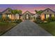 Stunning home exterior featuring lush landscaping, palm trees, brick driveway, and architectural design at sunset at 1182 Blue Shell Loop, Sarasota, FL 34240