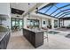 Outdoor kitchen island with bar seating and view of the pool and lounging area under a glass-paneled roof at 1182 Blue Shell Loop, Sarasota, FL 34240