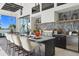 Outdoor kitchen and bar area with seating, stainless steel appliances, granite counters, and beautiful lake views at 1182 Blue Shell Loop, Sarasota, FL 34240