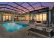A covered pool and lounge area features outdoor dining and entertaining, a fire pit, and water views at dusk at 1182 Blue Shell Loop, Sarasota, FL 34240