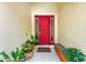A bright red front door is accented by potted plants and a built-in bench at 12175 Maple Ridge Dr, Parrish, FL 34219