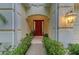 Inviting entryway with a bright red door framed by lush greenery and stylish outdoor lighting at 12175 Maple Ridge Dr, Parrish, FL 34219