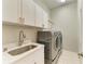 Well-equipped laundry room boasts modern washer, dryer, ample storage, and a convenient sink for easy chores at 12175 Maple Ridge Dr, Parrish, FL 34219