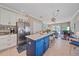 Modern kitchen showcasing a blue island, stainless steel fridge, and seamless flow to living area at 12322 Tall Pines Way, Lakewood Ranch, FL 34202