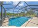 Enclosed pool area with blue tiled pool, lake view, and comfortable outdoor furniture at 12322 Tall Pines Way, Lakewood Ranch, FL 34202