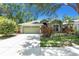 Charming one-story home with lush landscaping, green exterior, and a two-car garage at 135 Tall Trees Ct, Sarasota, FL 34232
