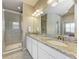 Bright bathroom featuring double sinks, granite countertops, and a glass-enclosed shower at 13710 Messina Loop # 201, Bradenton, FL 34211