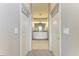 Hallway view of the dual sink bathroom featuring a shared mirror, cabinetry, and lighting at 13710 Messina Loop # 201, Bradenton, FL 34211