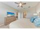 Bedroom featuring a ceiling fan, dresser with TV, and ensuite bathroom access for convenience at 13710 Messina Loop # 201, Bradenton, FL 34211