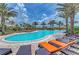 Large community pool with lounge chairs, umbrellas, and palm trees under a blue sky at 13710 Messina Loop # 201, Bradenton, FL 34211