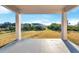 This covered back patio overlooks a sprawling backyard with a manicured lawn and mature trees under a blue sky at 14065 Paris Ln, Port Charlotte, FL 33981