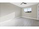 This bedroom features light gray walls, wood-look tile floors, a ceiling fan, and a window letting in natural light at 14065 Paris Ln, Port Charlotte, FL 33981