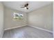 This bedroom features light gray walls, wood-look tile floors, a ceiling fan, and a window letting in natural light at 14065 Paris Ln, Port Charlotte, FL 33981