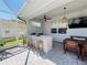 Outdoor kitchen under covered patio includes bar seating, built in grill, sink, and mounted television at 15207 Searobbin Dr, Lakewood Ranch, FL 34202