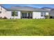Large backyard with green grass, a covered patio, and a sliding glass door at 17122 Ranchside Pl, Bradenton, FL 34211
