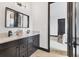 Bathroom with double sinks, dark fixtures, and a doorway that leads to a bedroom at 17122 Ranchside Pl, Bradenton, FL 34211