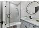 Modern bathroom featuring a glass-enclosed shower, gray vanity, and stylish round mirror at 17122 Ranchside Pl, Bradenton, FL 34211