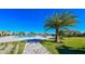 A scenic community pool area with palm trees, lounge chairs, and a rock waterfall feature on a sunny day at 17704 Gawthrop Dr # 303, Lakewood Ranch, FL 34211
