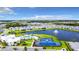 Aerial view of the community showcasing tennis courts, a pool, a lake, and multiple homes at 18510 Midsummer Pl, Venice, FL 34293