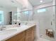 Bathroom showcasing double sinks, wood cabinets, and glass-enclosed shower at 18510 Midsummer Pl, Venice, FL 34293