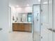 Beautiful bathroom with double sinks, wood cabinets, and a glass-enclosed shower at 18510 Midsummer Pl, Venice, FL 34293