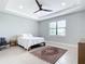 Bright bedroom features a tray ceiling, ceiling fan, and a window for natural light at 18510 Midsummer Pl, Venice, FL 34293