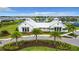 Beautiful clubhouse exterior with a lake, water fountain, palm trees, and lush landscaping at 18510 Midsummer Pl, Venice, FL 34293