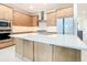 Modern kitchen featuring a center island, stainless steel appliances, and light wood cabinets at 18510 Midsummer Pl, Venice, FL 34293