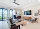 Bright living room with tile floors, a ceiling fan, large windows, and sliding glass doors at 18510 Midsummer Pl, Venice, FL 34293