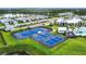Aerial view of blue tennis and pickleball courts surrounded by lush landscaping in a beautiful community at 18510 Midsummer Pl, Venice, FL 34293