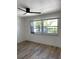 A bright bedroom with hardwood floors, a ceiling fan, and a large window at 1947 Los Lomas Dr, Clearwater, FL 33763