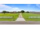 Exterior shot of the home showing long driveway, ample land, and white fencing bordering surrounding agricultural fields at 2350 Virgil Hall Rd, Lithia, FL 33547