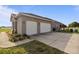 Exterior showcasing a three-car garage, neutral paint, driveway, and landscaping in a rural area at 2350 Virgil Hall Rd, Lithia, FL 33547