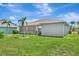 Home's backyard featuring lush lawn, tropical landscaping, and a screened lanai, perfect for relaxing outdoors at 24512 Bramhope Ct, Punta Gorda, FL 33980