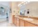 Bathroom featuring double sinks, granite countertops, wood cabinets, and a soaking tub at 24512 Bramhope Ct, Punta Gorda, FL 33980