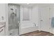 Bathroom showcasing a shower, and a white tub set against white tile at 2816 Breton Woods, Sarasota, FL 34235