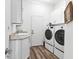 Well-lit laundry room with modern washer and dryer, cabinet storage, and wash sink at 2816 Breton Woods, Sarasota, FL 34235