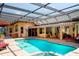 Backyard view of screened-in pool with brick patio and covered seating area with clear roof at 2901 Little Country Rd, Parrish, FL 34219