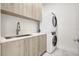 Bright laundry room with modern washer, dryer, and wood cabinets at 33 S Palm Ave # 1101, Sarasota, FL 34236