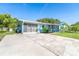 Lovely blue home featuring a large concrete driveway that leads to the screened front porch and a convenient garage at 3585 Brooklyn Ave, Port Charlotte, FL 33952