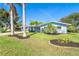 Charming blue home featuring a well-manicured lawn, beautiful landscaping, and a classic, screened front porch at 3585 Brooklyn Ave, Port Charlotte, FL 33952